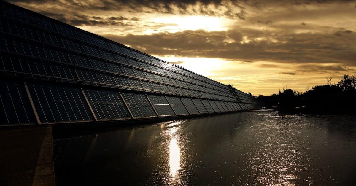 Silhouetted solar panels reflect sunset in tranquil waters, showcasing renewable energy.