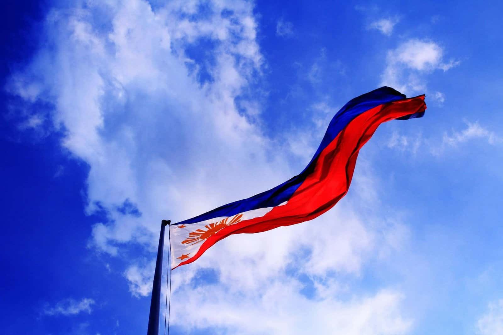 Philippine flag waving against a bright blue sky, symbolizing patriotism and freedom.